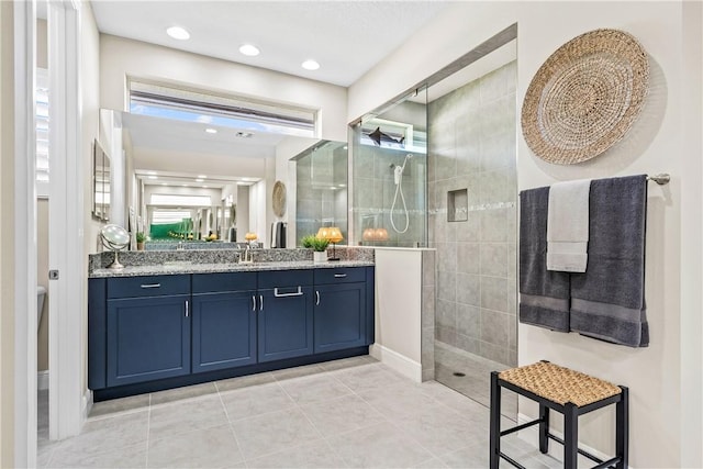 bathroom featuring tile patterned flooring, vanity, and tiled shower