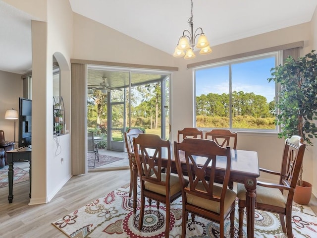 dining area featuring ceiling fan with notable chandelier, light wood-type flooring, and vaulted ceiling