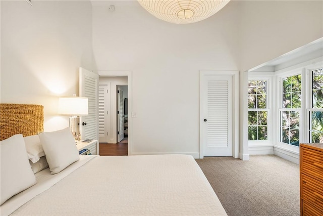 bedroom featuring a high ceiling, baseboards, and carpet floors