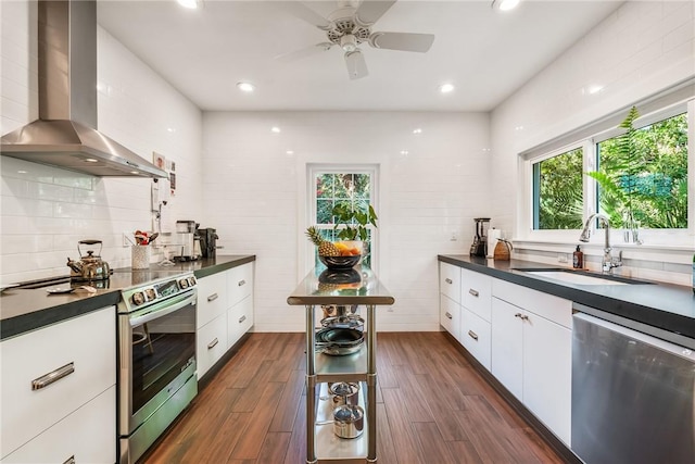 kitchen with a sink, dark countertops, wall chimney exhaust hood, and stainless steel appliances