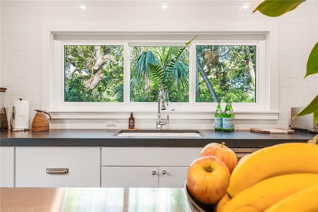 interior space with a sink, dark countertops, and white cabinets