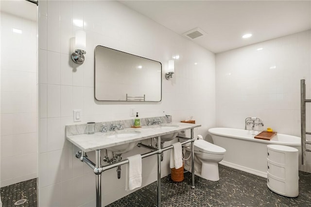 bathroom with visible vents, a tub, toilet, tile walls, and a sink