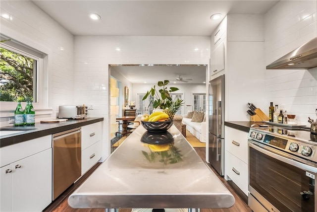 kitchen featuring dark countertops, white cabinets, stainless steel appliances, and backsplash