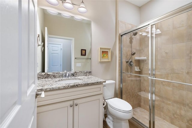 full bathroom featuring toilet, a stall shower, and vanity