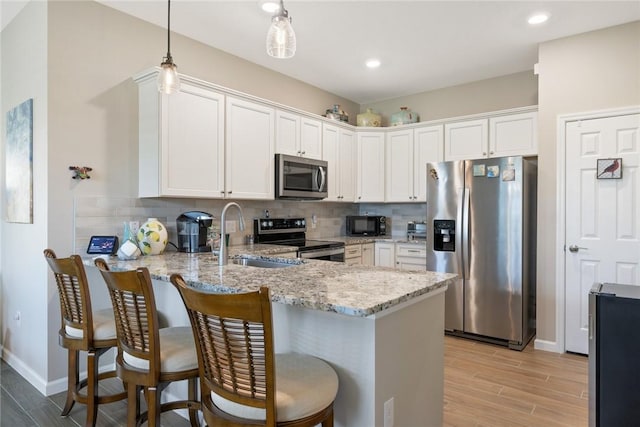 kitchen featuring appliances with stainless steel finishes, a sink, a peninsula, and decorative backsplash