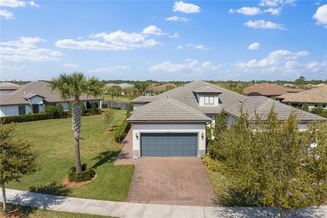 view of front of property with decorative driveway, a tile roof, stucco siding, a front yard, and a garage