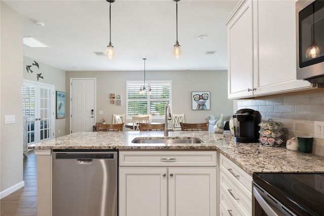 kitchen featuring a peninsula, a sink, white cabinetry, appliances with stainless steel finishes, and backsplash