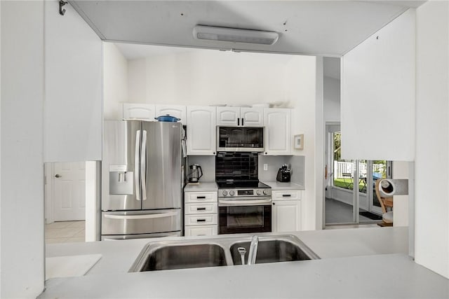 kitchen featuring white cabinets, a sink, stainless steel appliances, light countertops, and backsplash