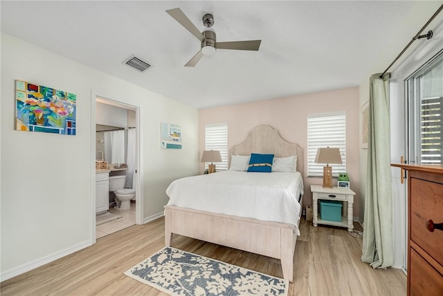 bedroom with ensuite bathroom, multiple windows, light wood-type flooring, and visible vents