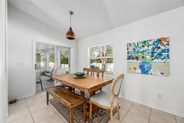 dining space featuring light tile patterned floors, baseboards, and vaulted ceiling