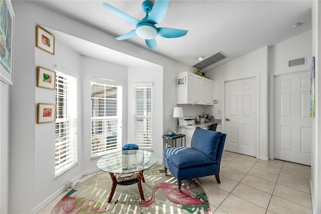 sitting room featuring light tile patterned floors, a textured ceiling, lofted ceiling, visible vents, and a ceiling fan