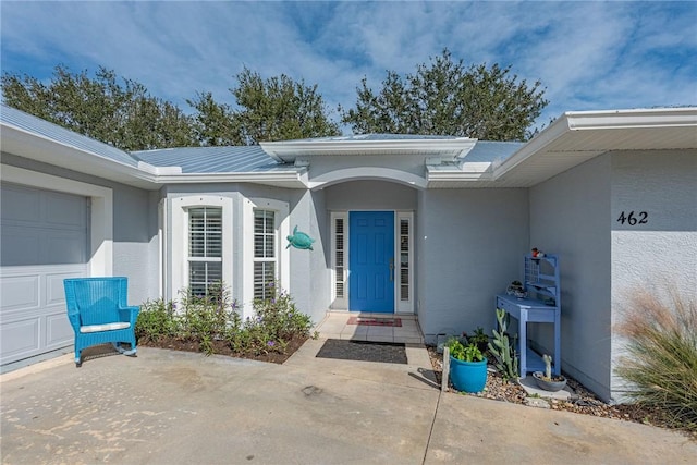 entrance to property with a garage and stucco siding