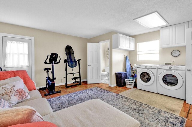 laundry area with cabinet space, baseboards, washer and clothes dryer, a textured ceiling, and light tile patterned flooring