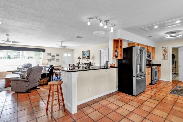 kitchen with ceiling fan, stainless steel appliances, dark countertops, and a peninsula