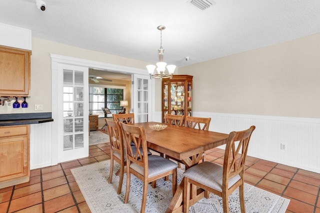 dining space with wainscoting, visible vents, a notable chandelier, and light tile patterned floors