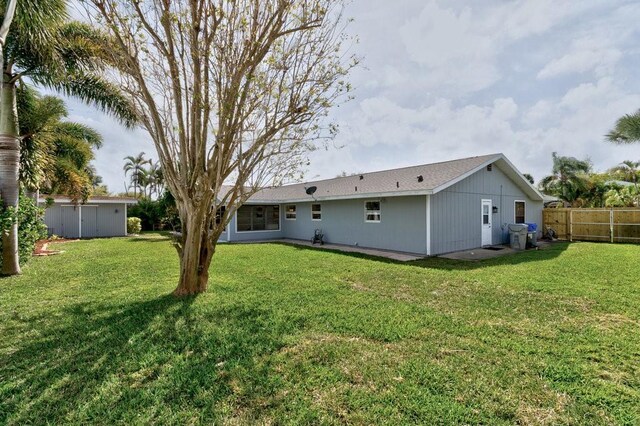 back of property with a lawn and fence