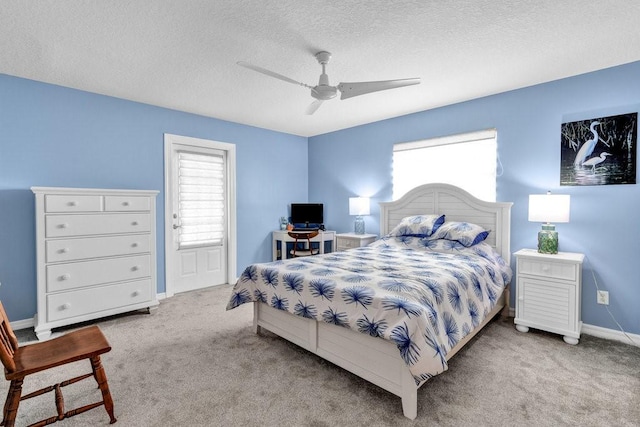 carpeted bedroom with ceiling fan, baseboards, and a textured ceiling