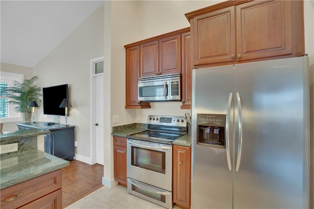 kitchen with lofted ceiling, stainless steel appliances, light parquet flooring, and stone counters