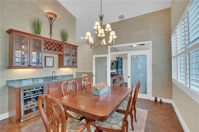 dining room featuring wine cooler, a towering ceiling, dark parquet floors, and indoor wet bar