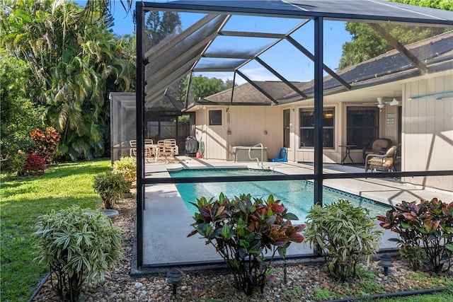 view of swimming pool with glass enclosure, ceiling fan, and a patio