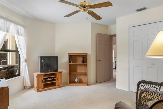 living area with light carpet and ceiling fan