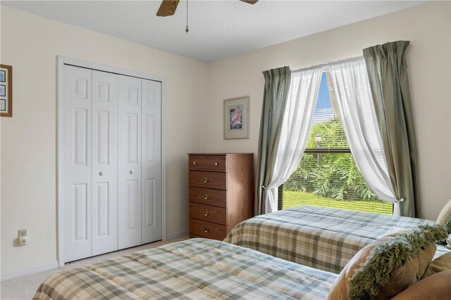 carpeted bedroom with ceiling fan and a closet