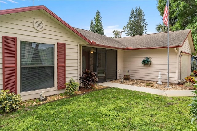 back of property featuring a garage and a lawn