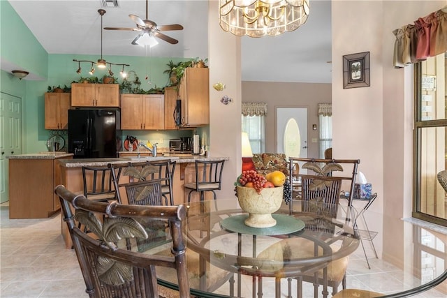 tiled dining area with ceiling fan with notable chandelier and a healthy amount of sunlight