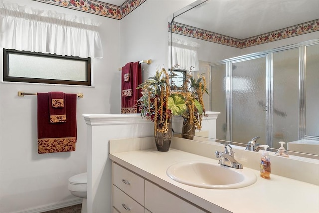 bathroom featuring vanity, toilet, and a shower with shower door