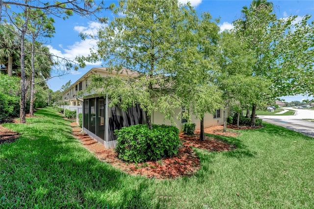 view of side of home featuring a lawn and a sunroom