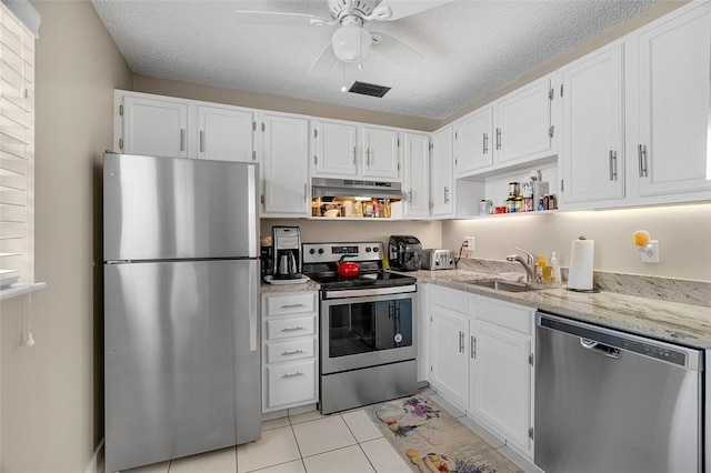 kitchen with white cabinetry, stainless steel appliances, light stone countertops, and sink