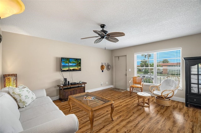 living room with ceiling fan, wood-type flooring, and a textured ceiling