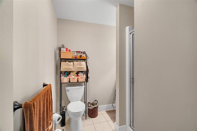 bathroom featuring toilet, an enclosed shower, and tile patterned flooring