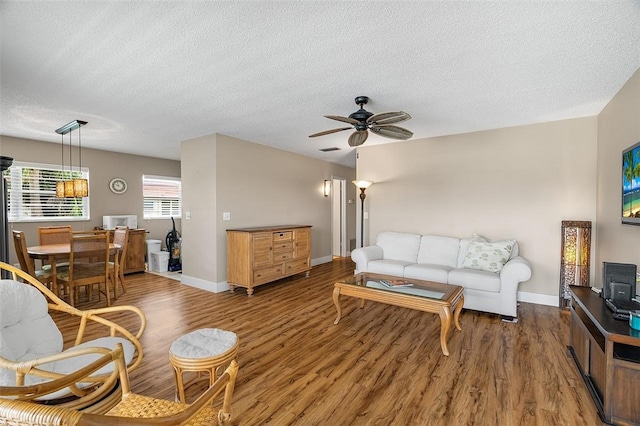 living room with ceiling fan, dark hardwood / wood-style floors, and a textured ceiling