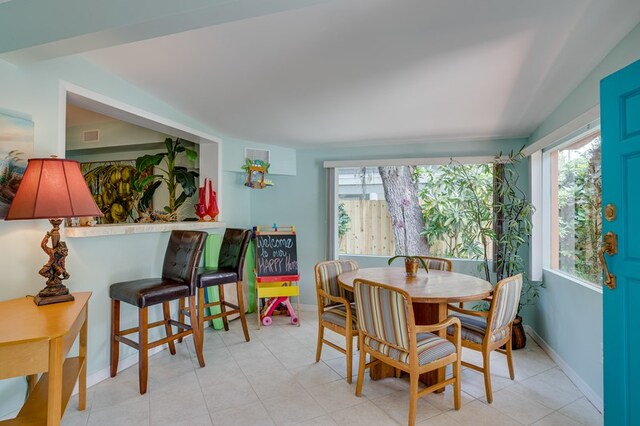 dining room featuring vaulted ceiling and light tile patterned flooring