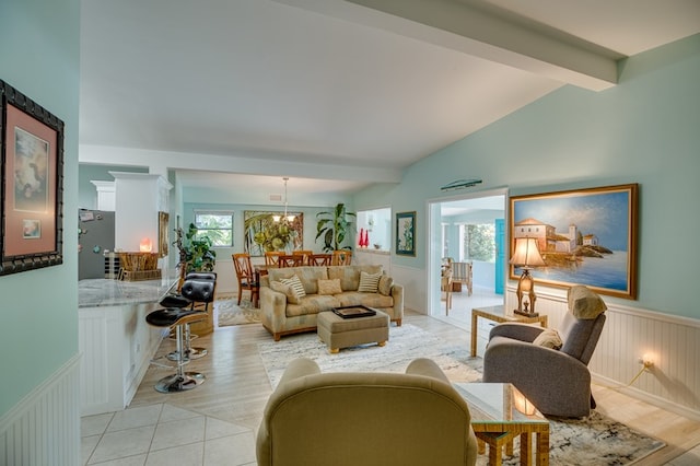 living room featuring vaulted ceiling with beams, a notable chandelier, and light wood-type flooring