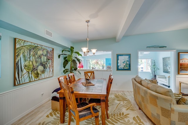 dining space with beamed ceiling, plenty of natural light, light hardwood / wood-style floors, and a chandelier