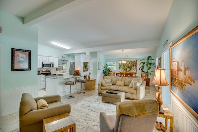 living room with vaulted ceiling with beams, light hardwood / wood-style floors, and an inviting chandelier