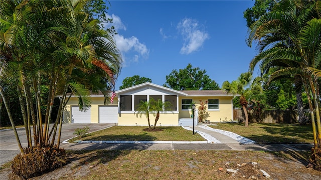 view of front of home featuring a garage, a front yard, and a sunroom