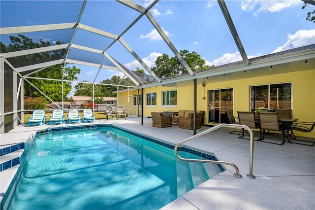 view of pool with a patio area, glass enclosure, outdoor lounge area, and pool water feature