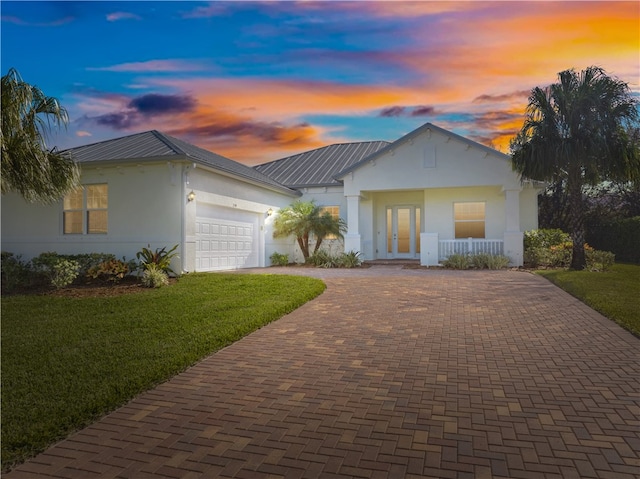 ranch-style home with covered porch, a garage, and a lawn