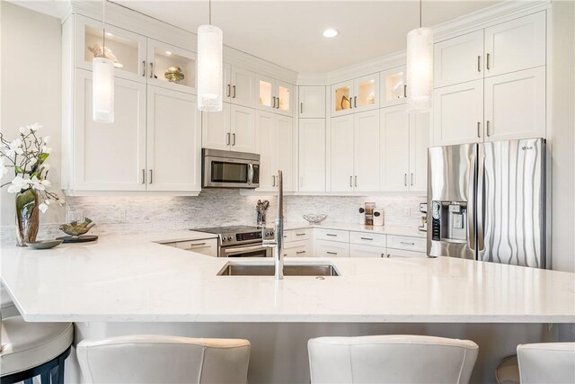 kitchen with stainless steel appliances, sink, a kitchen island with sink, and white cabinets