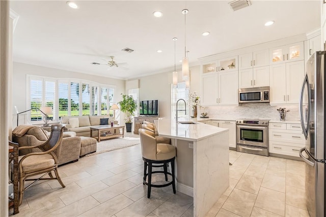 860 Saint James Ln, Vero Beach, FL 32967 - kitchen featuring appliances with stainless steel finishes, open floor plan, a sink, tasteful backsplash, and a breakfast bar