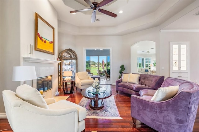 living room featuring a tiled fireplace, ceiling fan, dark hardwood / wood-style floors, and a healthy amount of sunlight