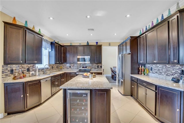 kitchen featuring light stone counters, sink, beverage cooler, and appliances with stainless steel finishes