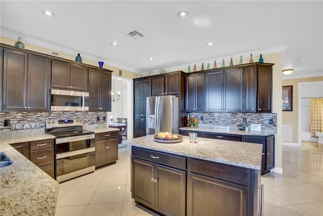 kitchen featuring crown molding, light stone countertops, light tile patterned floors, appliances with stainless steel finishes, and dark brown cabinets