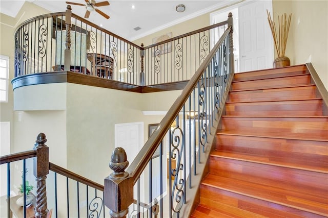 stairway with ceiling fan, a towering ceiling, and ornamental molding