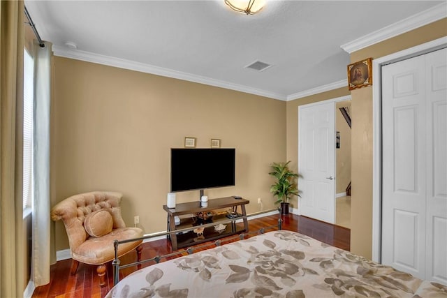 bedroom with hardwood / wood-style floors, ornamental molding, and a closet