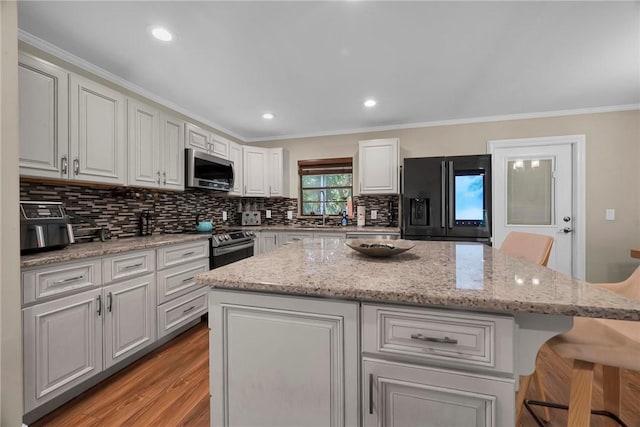 1966 9th St, Vero Beach, FL 32960 - kitchen with stainless steel appliances, a kitchen island, backsplash, a kitchen breakfast bar, and light wood-style flooring