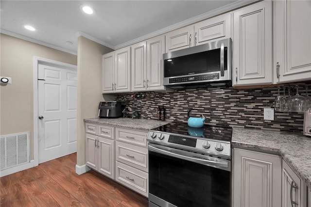 1966 9th St, Vero Beach, FL 32960 - kitchen featuring stainless steel appliances, ornamental molding, backsplash, wood finished floors, and white cabinetry